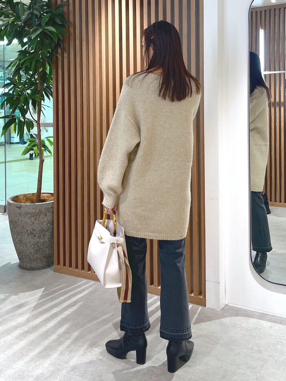 ベージュ系のワンピース、ブラック系のデニムパンツ、ホワイト系のショルダーバッグを着用したレディースの冬コーディネートの7枚目の写真