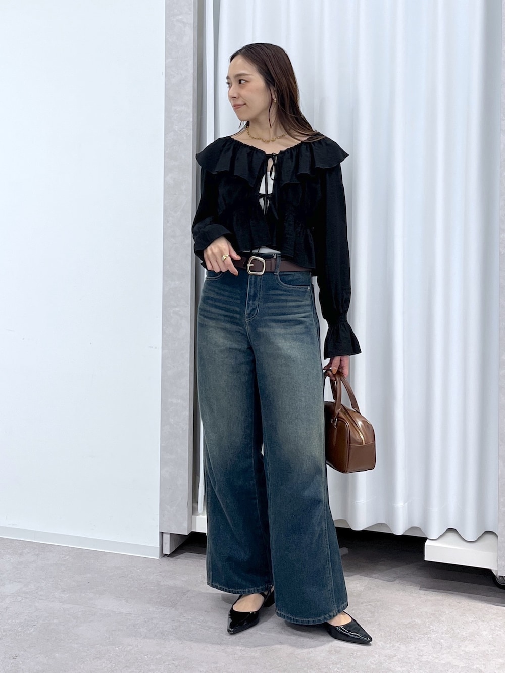 ブラック系のシャツ/ブラウス、ブルー系のデニムパンツ、ブラウン系のハンドバッグを着用したレディースの春コーディネートの2枚目の写真