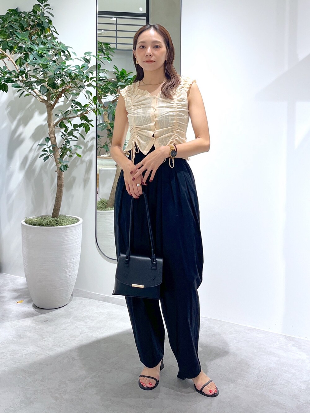 ブラック系のショルダーバッグ、ブラック系のパンツ、イエロー系のシャツ/ブラウスを着用したレディースの夏コーディネートの2枚目の写真