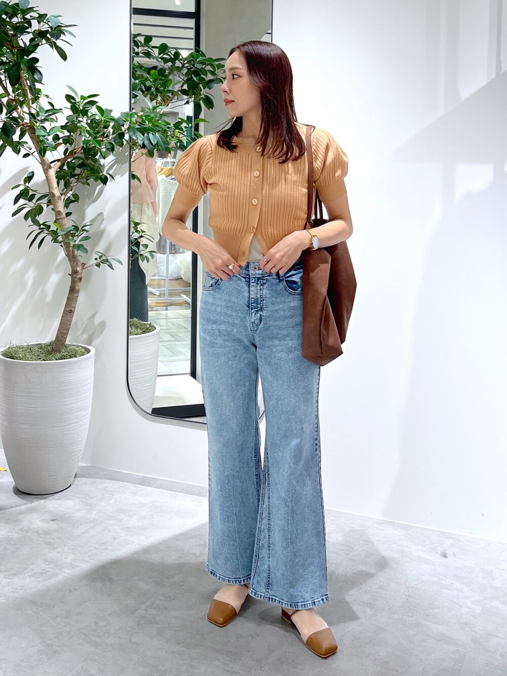 オレンジ系のTシャツ/カットソー、ブラウン系のトートバッグ、ブルー系のデニムパンツを着用したレディースの春コーディネートの9枚目の写真