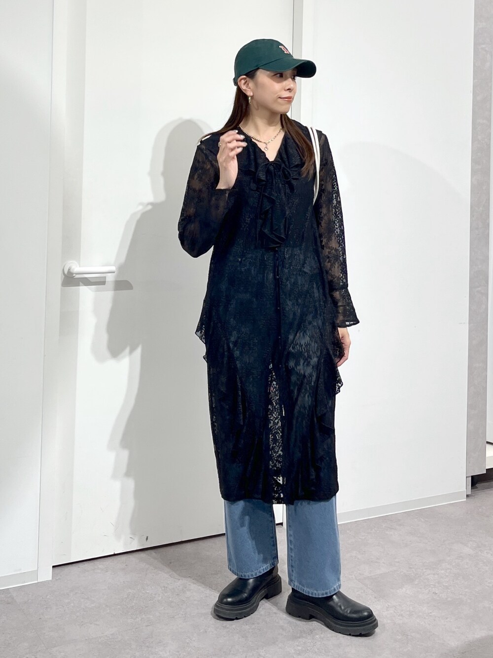 ホワイト系のショルダーバッグ、ブラック系のワンピース、ブルー系のデニムパンツを着用したレディースの冬コーディネートの8枚目の写真