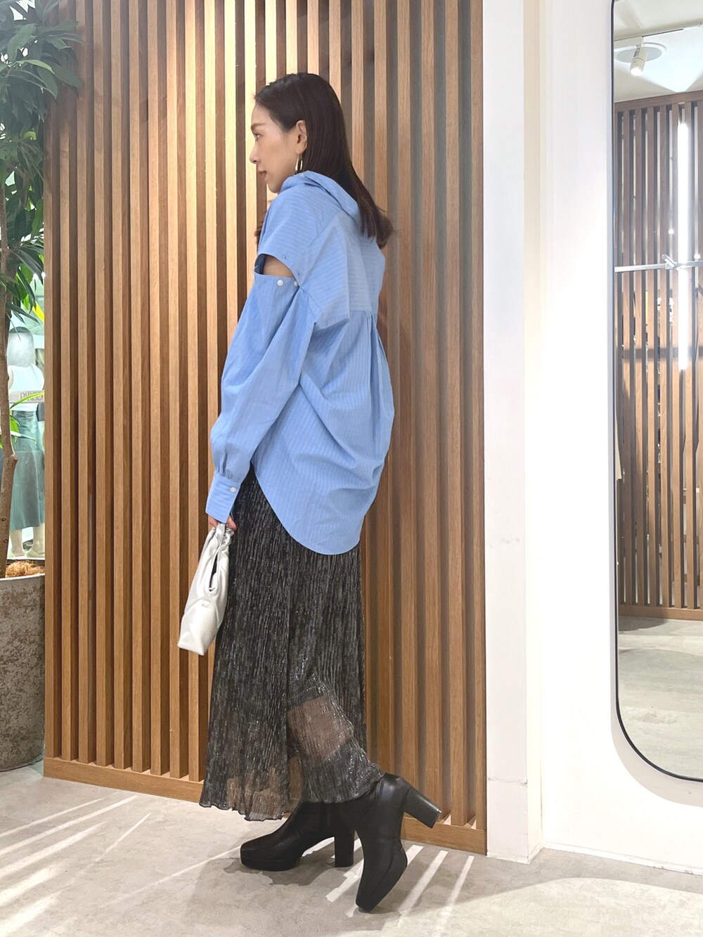 ブルー系のシャツ/ブラウス、ブラック系のスカート、シルバー系のショルダーバッグを着用したレディースの秋コーディネートの2枚目の写真