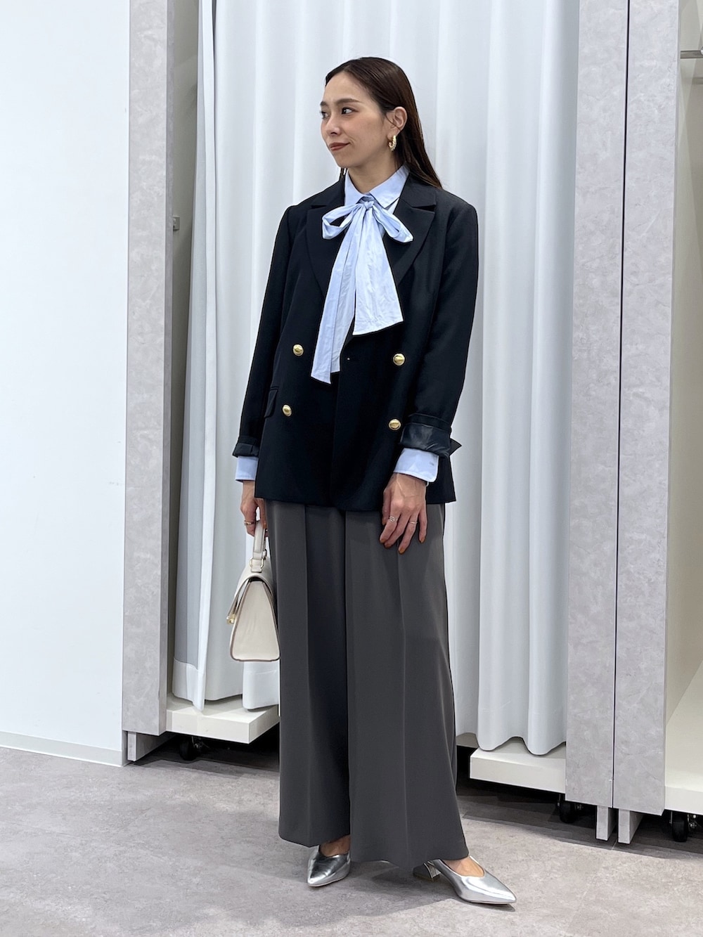 シルバー系のパンプス、グレー系のスラックス、ホワイト系のショルダーバッグを着用したレディースの冬コーディネートの7枚目の写真