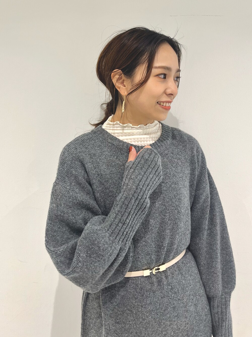 ホワイト系のショルダーバッグ、グレー系のワンピース、ブラック系のブーツを着用したレディースの冬コーディネートの3枚目の写真