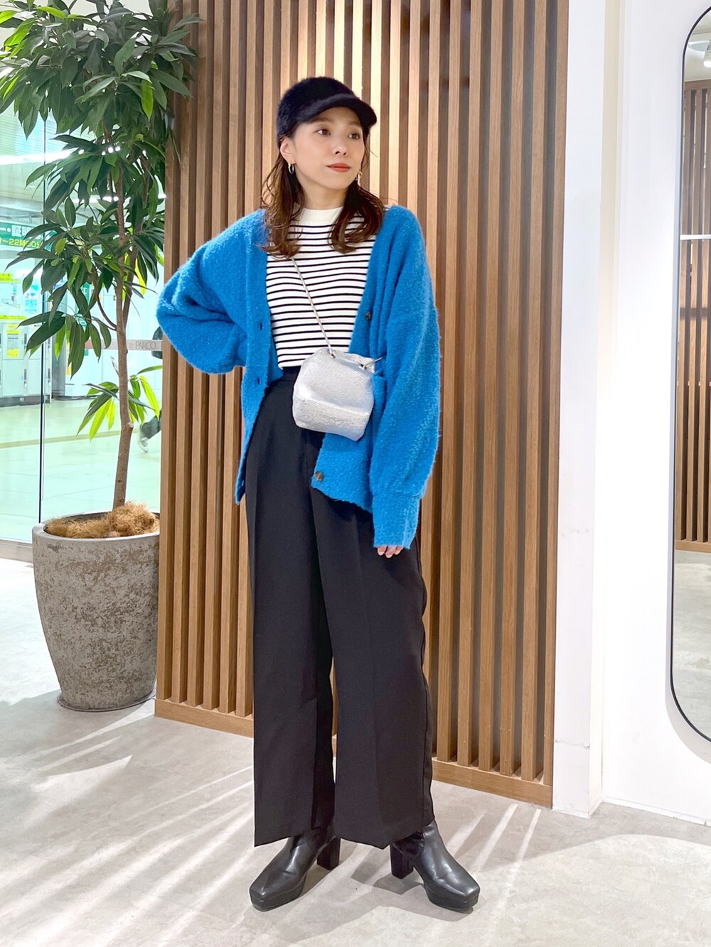 ブルー系のカーディガン/ボレロ、ホワイト系のニット/セーター、ブラック系のスラックスを着用したレディースの秋コーディネートの2枚目の写真