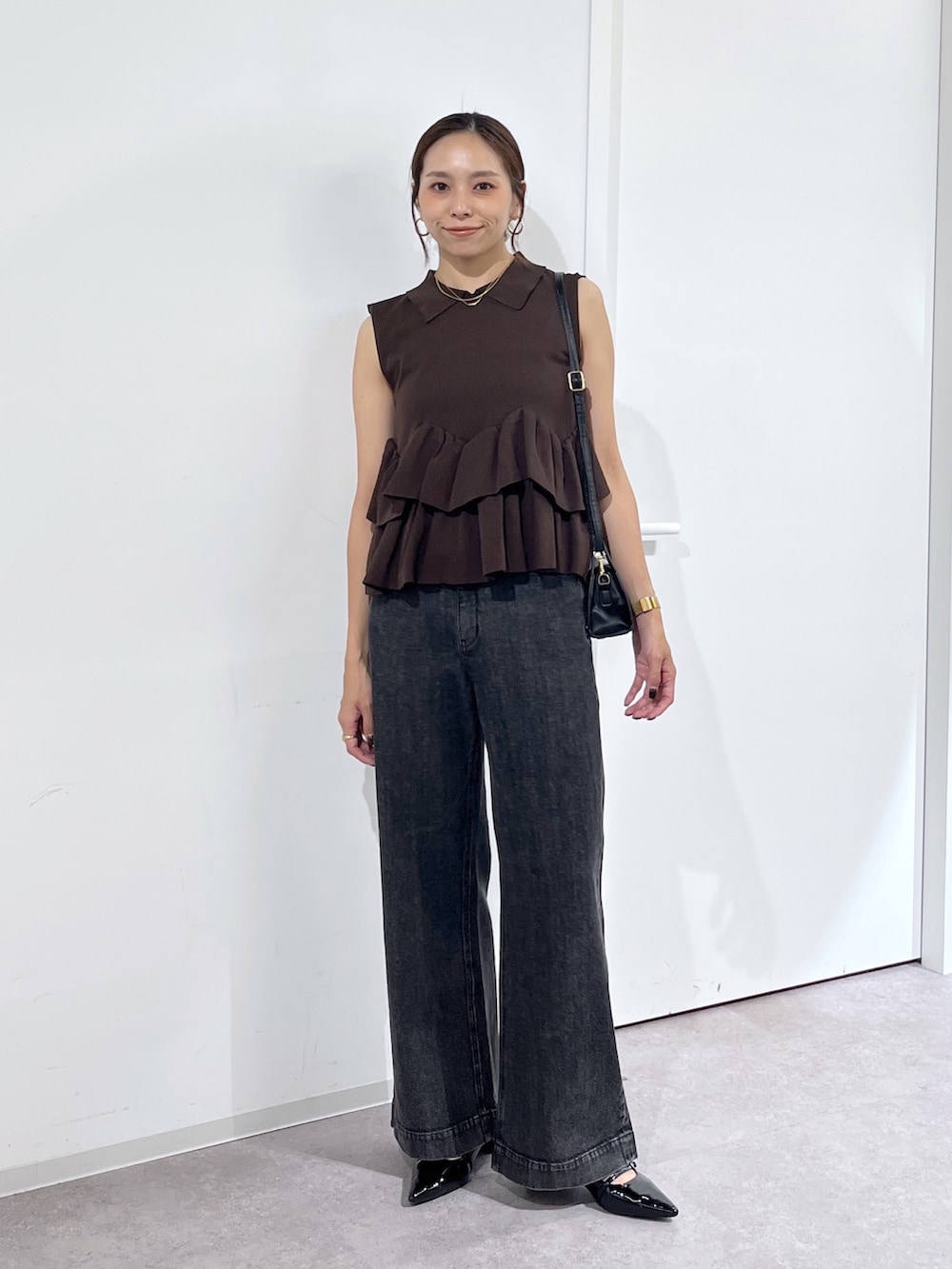 ブラック系のショルダーバッグ、ブラウン系のニット/セーター、ブラック系のデニムパンツを着用したレディースの夏コーディネートの2枚目の写真