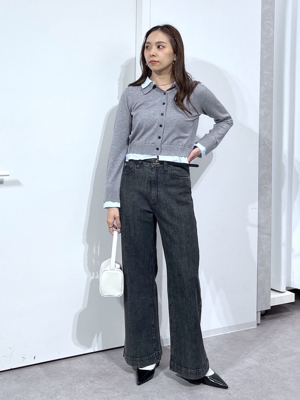 グレー系のニット/セーター、ホワイト系のハンドバッグ、ブラック系のデニムパンツを着用したレディースの春コーディネートの4枚目の写真