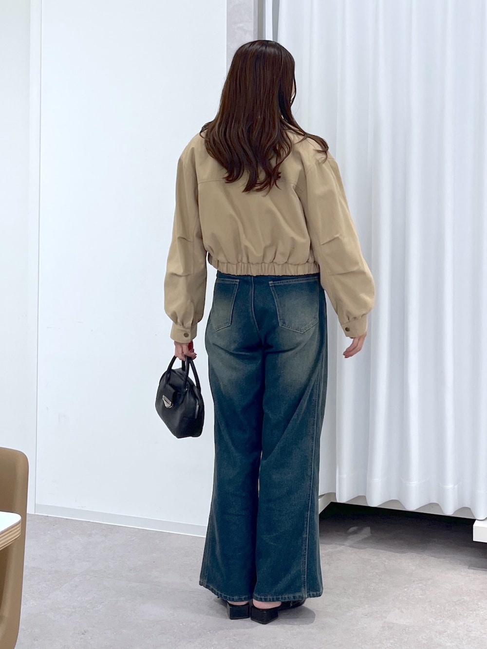 ベージュ系のブルゾン、ホワイト系のニット/セーター、ブルー系のデニムパンツを着用したレディースの春コーディネートの4枚目の写真