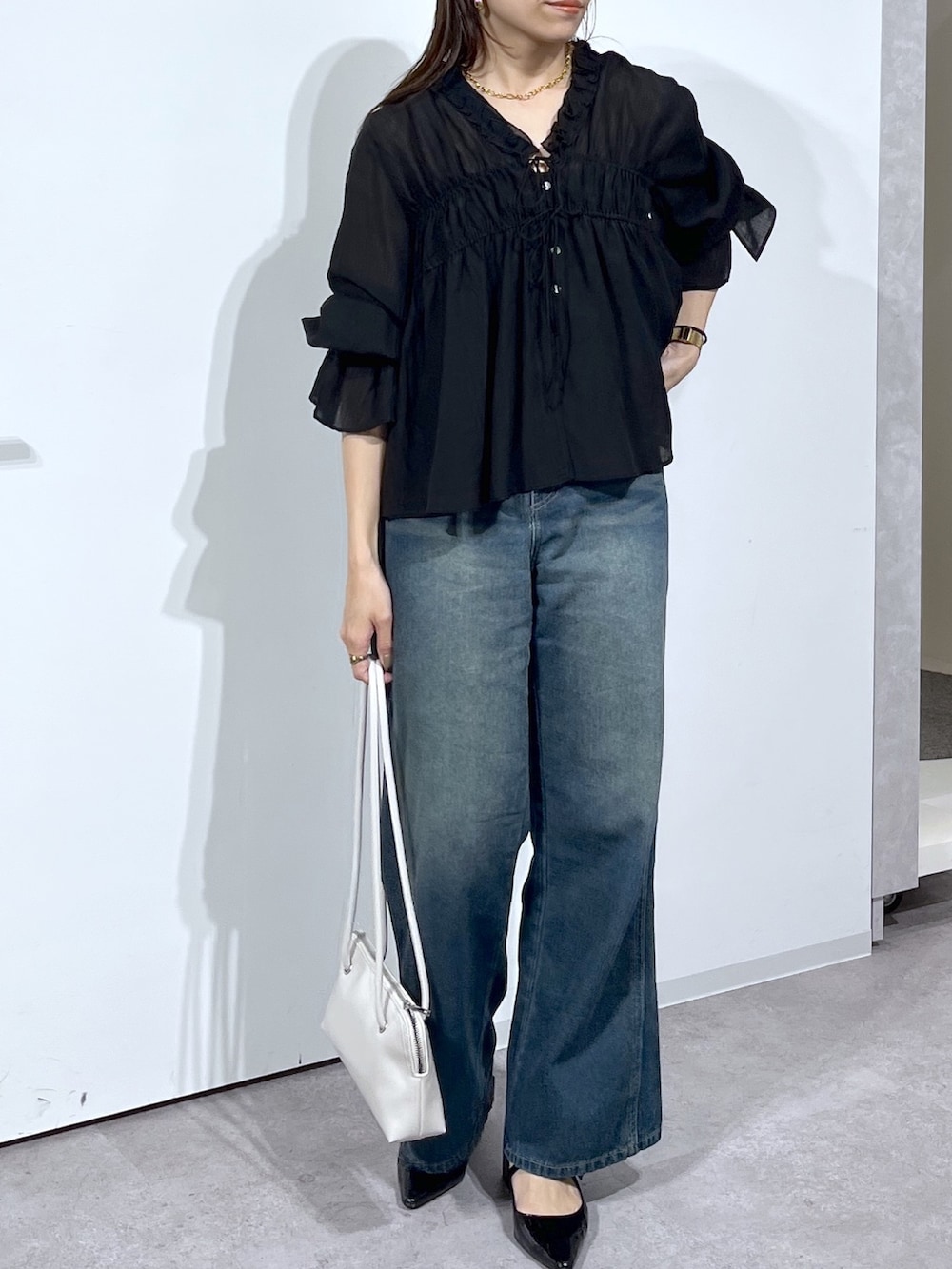 ブラック系のシャツ/ブラウス、ブルー系のデニムパンツを着用したレディースの春コーディネートの7枚目の写真