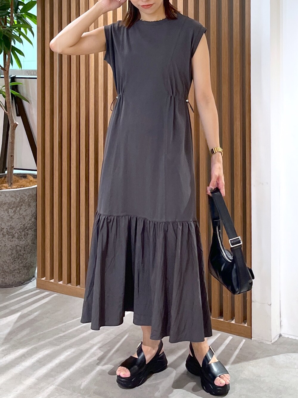 ブラック系のワンピース、ホワイト系のシャツ/ブラウス、ブラック系のサンダルを着用したレディースの夏コーディネートの4枚目の写真