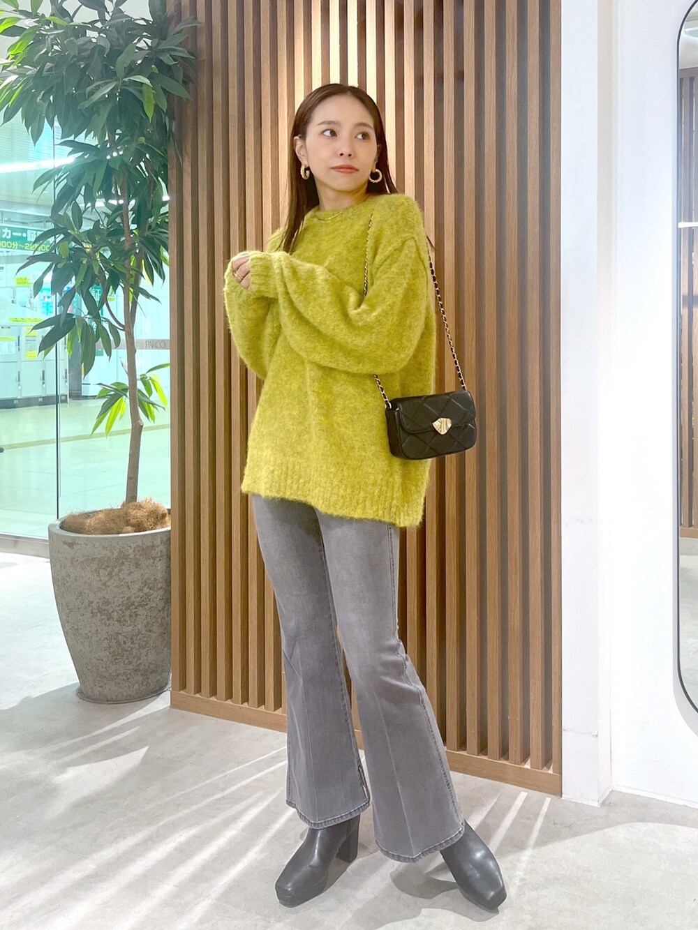 イエロー系のニット/セーター、ブラック系のデニムパンツ、ブラック系のショルダーバッグを着用したレディースの秋コーディネートの3枚目の写真