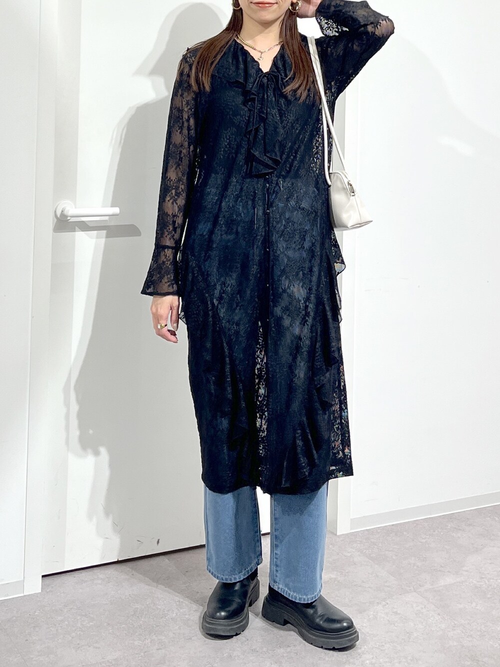 ホワイト系のショルダーバッグ、ブラック系のワンピース、ブルー系のデニムパンツを着用したレディースの冬コーディネートの5枚目の写真