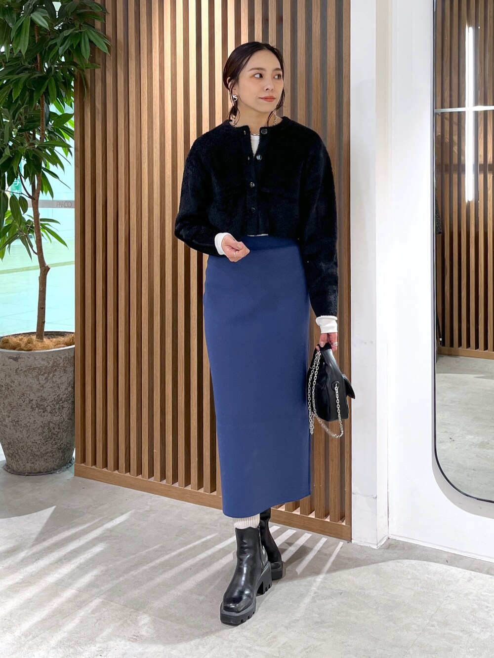 ブラック系のカーディガン/ボレロ、ブラック系のショルダーバッグ、ブルー系のスカートを着用したレディースの冬コーディネートの7枚目の写真