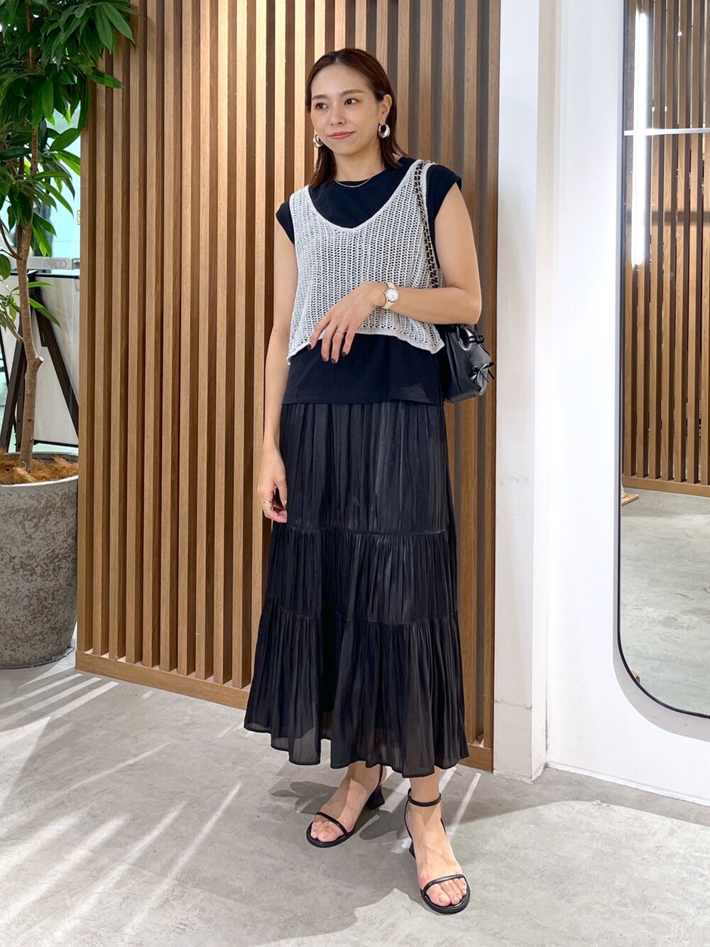 ブラック系のサンダル、ブラック系のスカート、ブラック系のショルダーバッグを着用したレディースの夏コーディネートの3枚目の写真