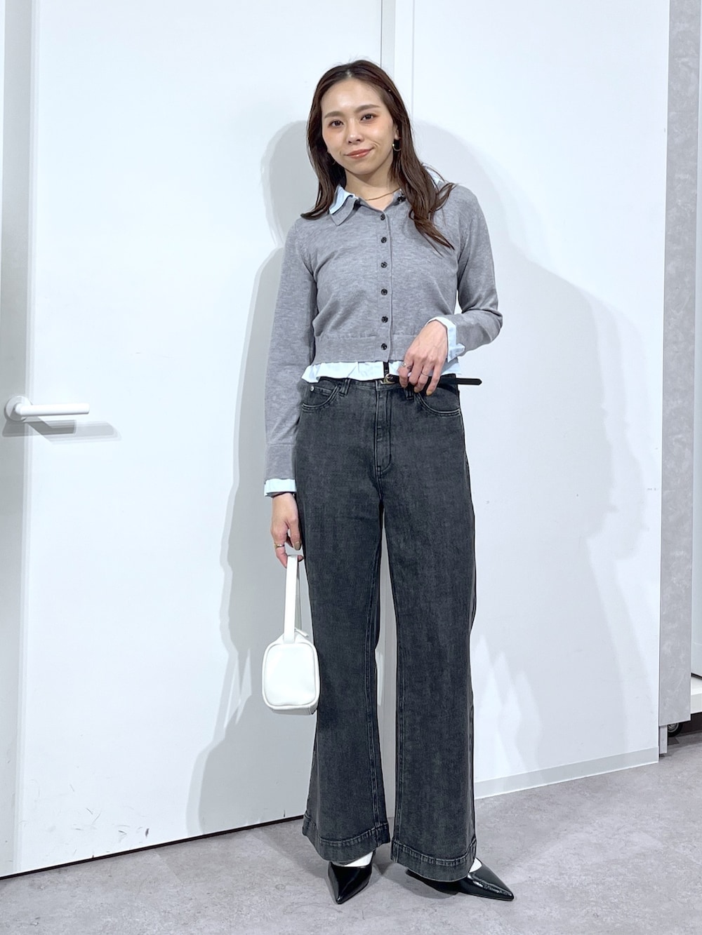 グレー系のニット/セーター、ホワイト系のハンドバッグ、ブラック系のデニムパンツを着用したレディースの春コーディネートの2枚目の写真