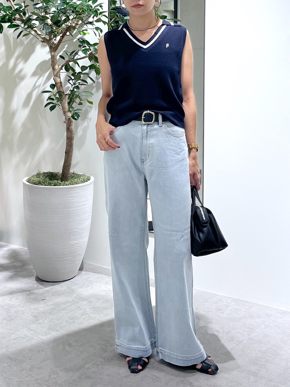 ブルー系のニット/セーター、ブルー系のデニムパンツ、ブラック系のショルダーバッグを着用したレディースの夏コーディネートの7枚目の写真