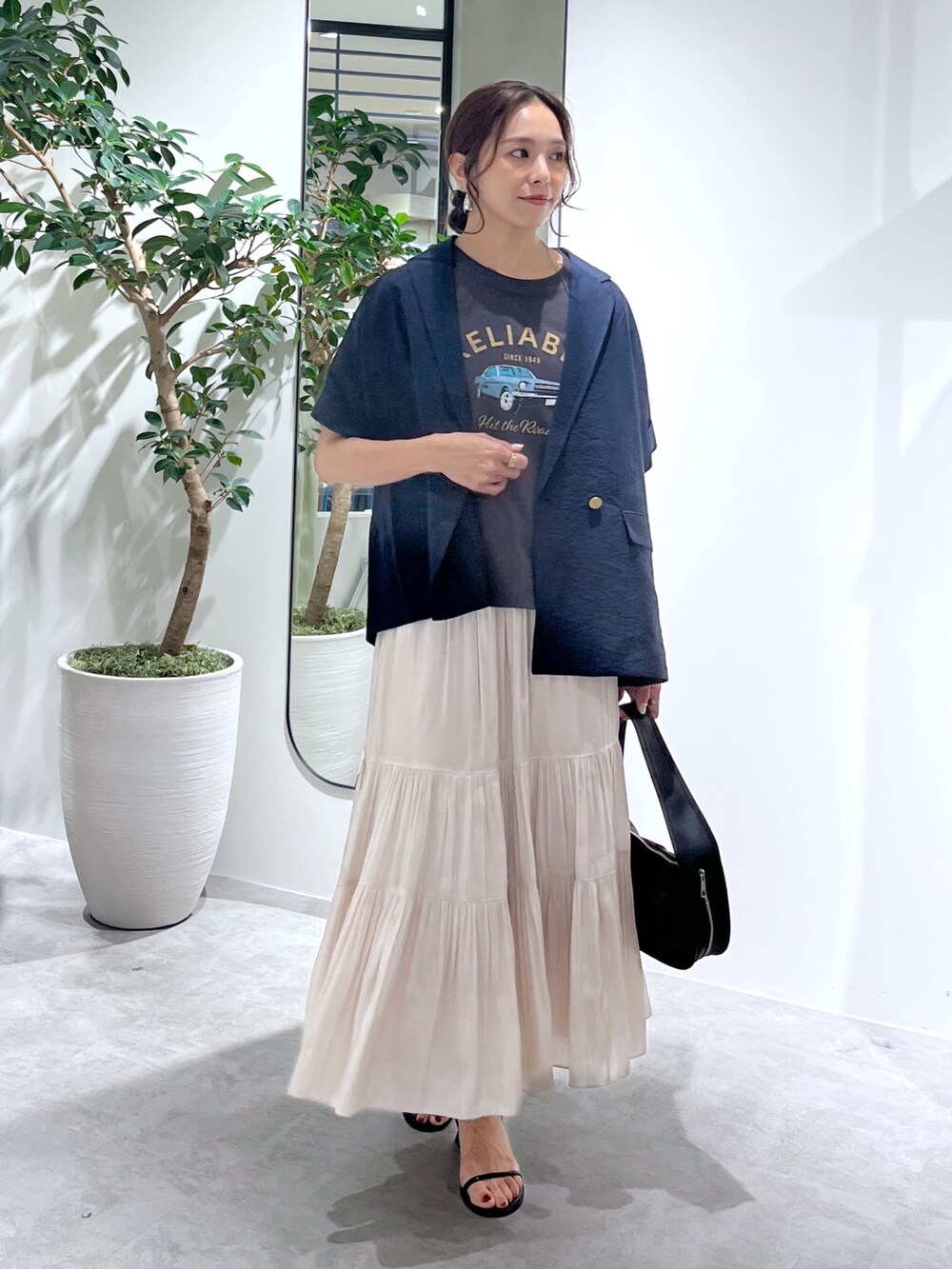 ブルー系のテーラードジャケット、ブラック系のハンドバッグ、ホワイト系のスカートを着用したレディースの夏コーディネートの3枚目の写真