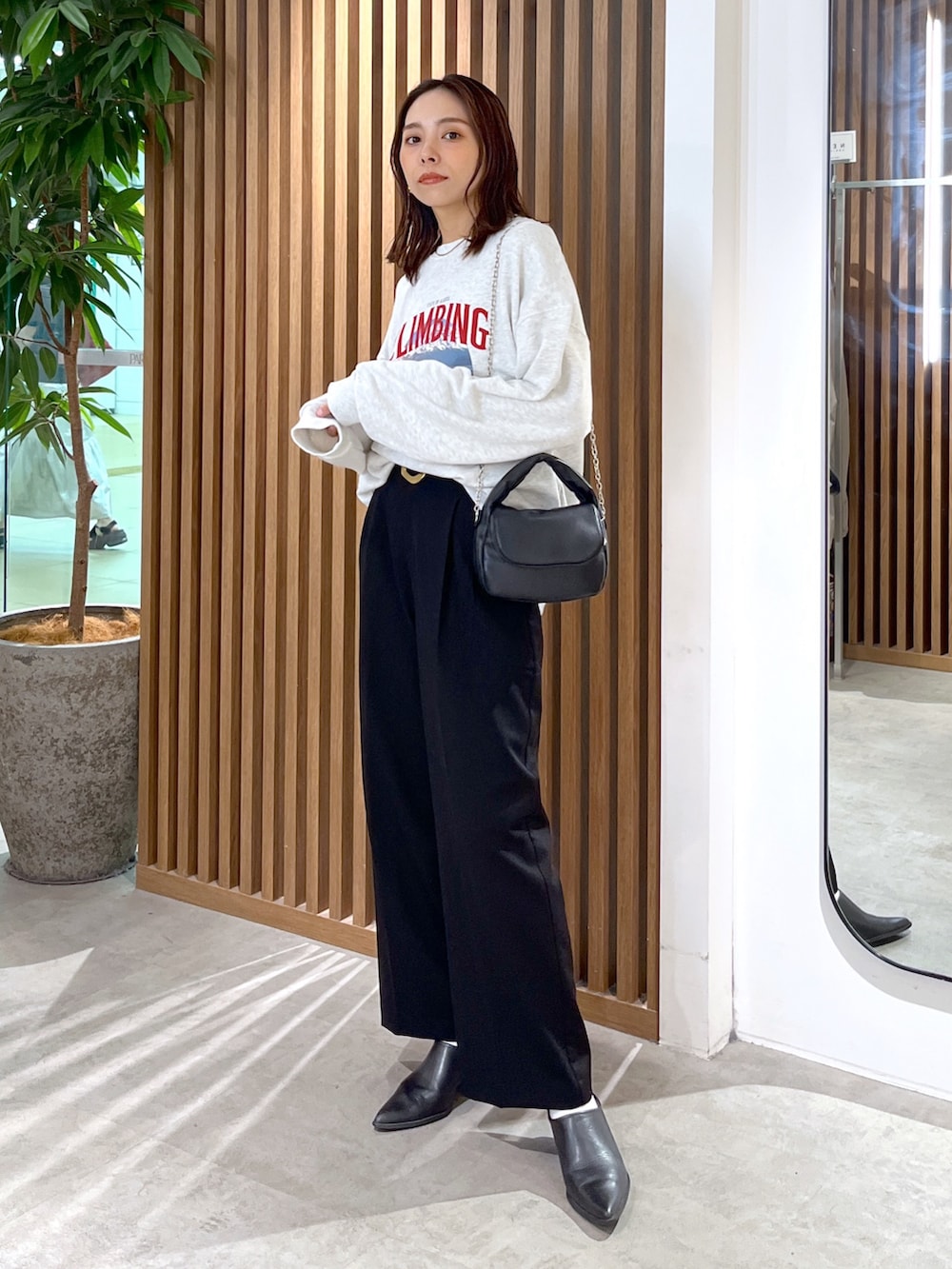 ホワイト系のスウェット、ブラック系のショルダーバッグ、ブラック系のスラックスを着用したレディースの秋コーディネートの8枚目の写真