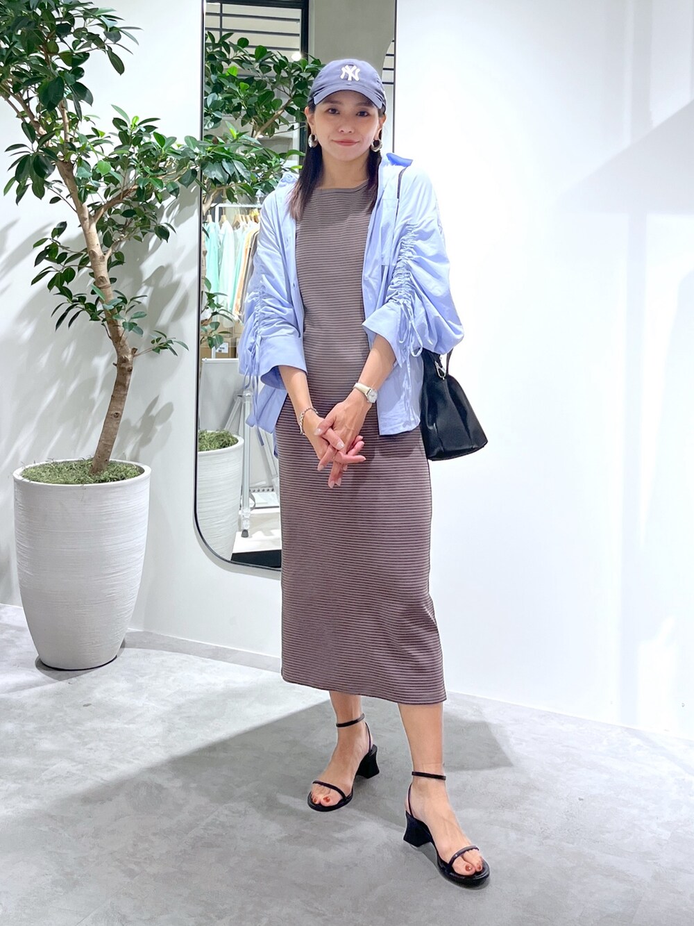 ブラウン系のワンピース、ブルー系のシャツ/ブラウス、ブラック系のショルダーバッグを着用したレディースの春コーディネートの9枚目の写真