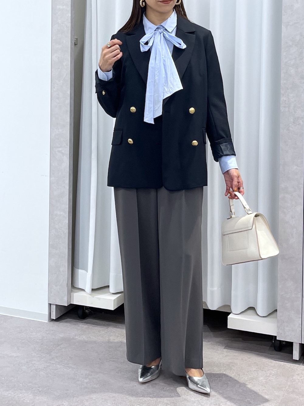 シルバー系のパンプス、グレー系のスラックス、ホワイト系のショルダーバッグを着用したレディースの冬コーディネートの4枚目の写真