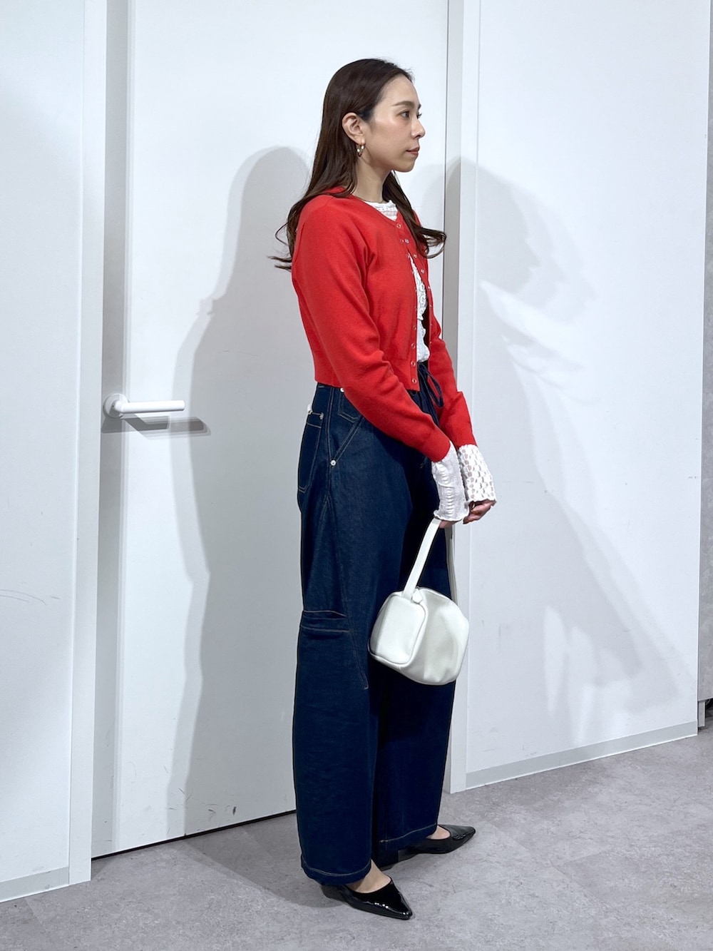 ホワイト系のTシャツ/カットソー、レッド系のニット/セーター、ブルー系のデニムパンツを着用したレディースの春コーディネートの4枚目の写真