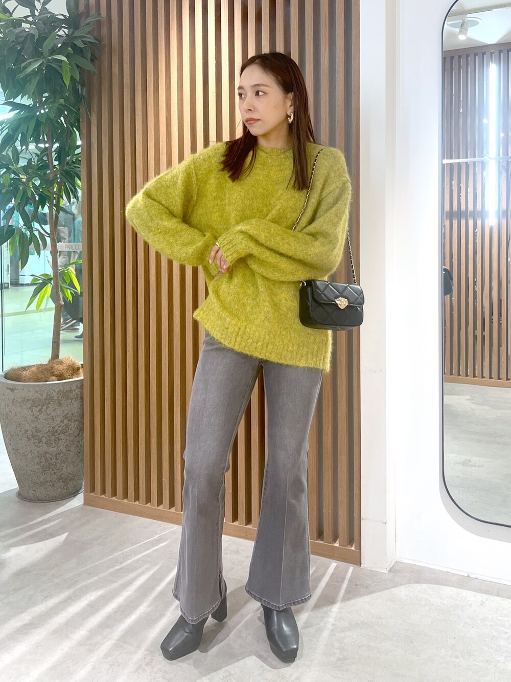 イエロー系のニット/セーター、ブラック系のデニムパンツ、ブラック系のショルダーバッグを着用したレディースの秋コーディネートの2枚目の写真