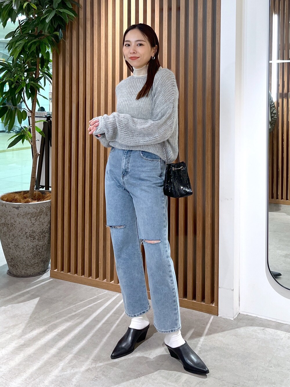 グレー系のニット/セーター、ホワイト系のTシャツ/カットソー、ブルー系のデニムパンツを着用したレディースの冬コーディネートの8枚目の写真