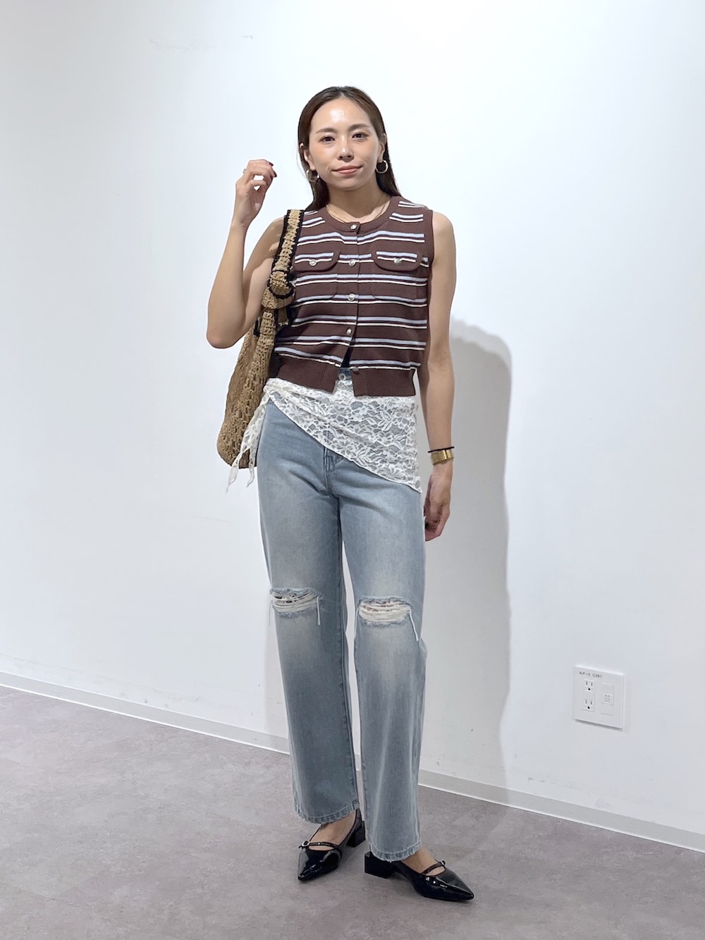 ブラウン系のニット/セーター、ブラック系のパンプス、ブルー系のデニムパンツを着用したレディースの夏コーディネートの3枚目の写真