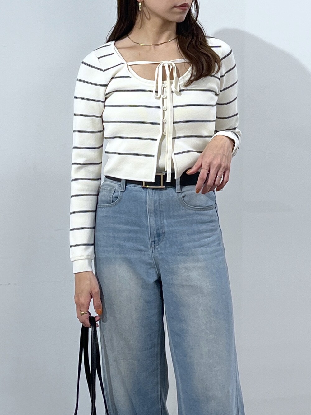 ブラック系のショルダーバッグ、ホワイト系のニット/セーター、ブルー系のデニムパンツを着用したレディースの冬コーディネートの5枚目の写真