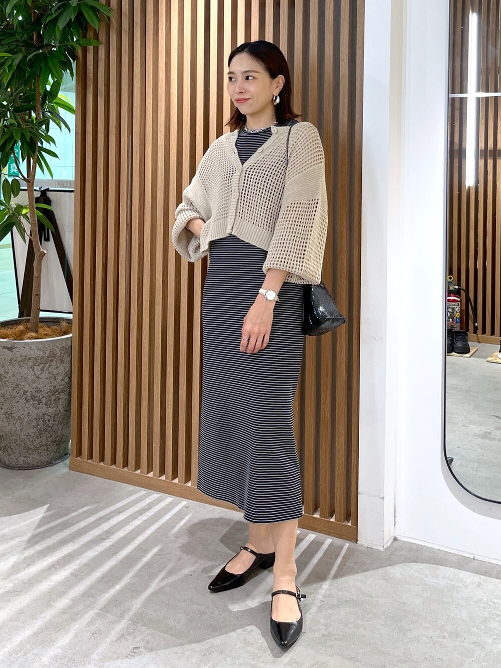 ベージュ系のカーディガン/ボレロ、ブラック系のショルダーバッグ、ブラック系のワンピースを着用したレディースの春コーディネートの3枚目の写真