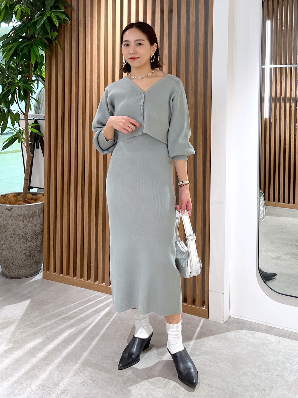 グリーン系のカーディガン/ボレロ、シルバー系のショルダーバッグ、グリーン系のワンピースを着用したレディースの冬コーディネートの2枚目の写真