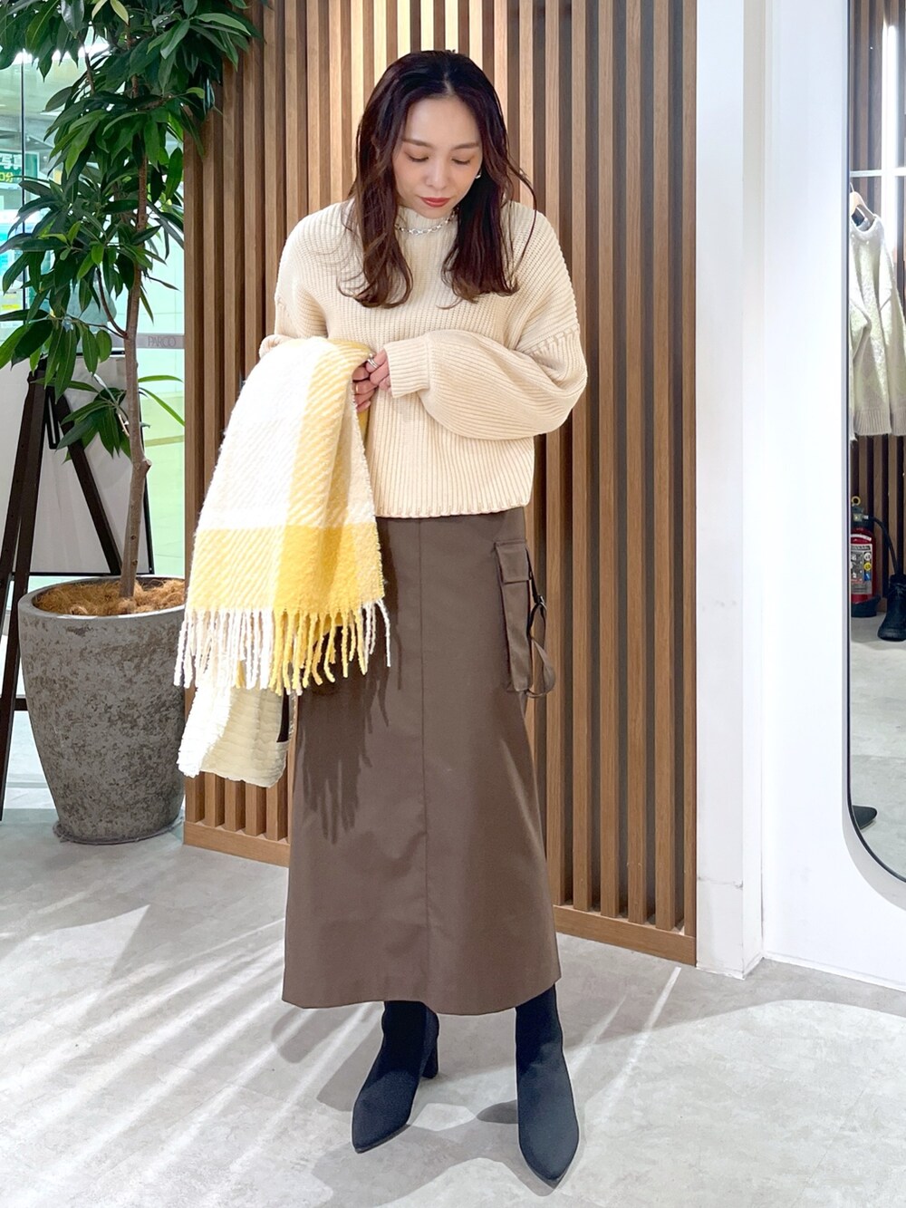 ブラウン系のスカート、ホワイト系のトートバッグ、ホワイト系のニット/セーターを着用したレディースの冬コーディネートの2枚目の写真
