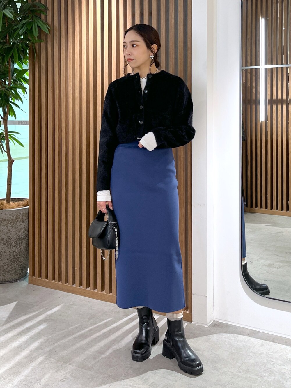 ブラック系のカーディガン/ボレロ、ブラック系のショルダーバッグ、ブルー系のスカートを着用したレディースの冬コーディネートの9枚目の写真