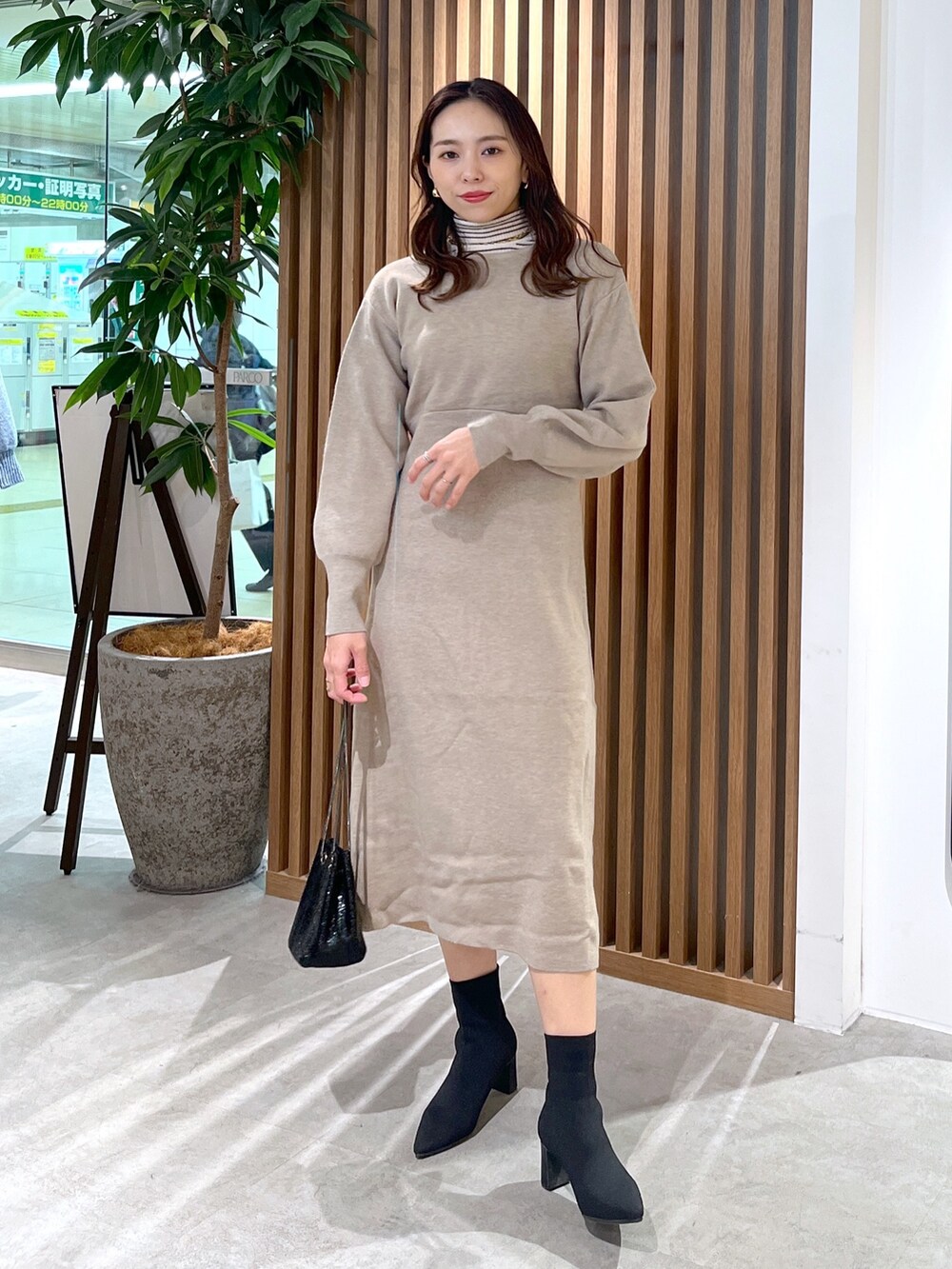 ブラック系のショルダーバッグ、ベージュ系のワンピース、ホワイト系のニット/セーターを着用したレディースの冬コーディネートの2枚目の写真