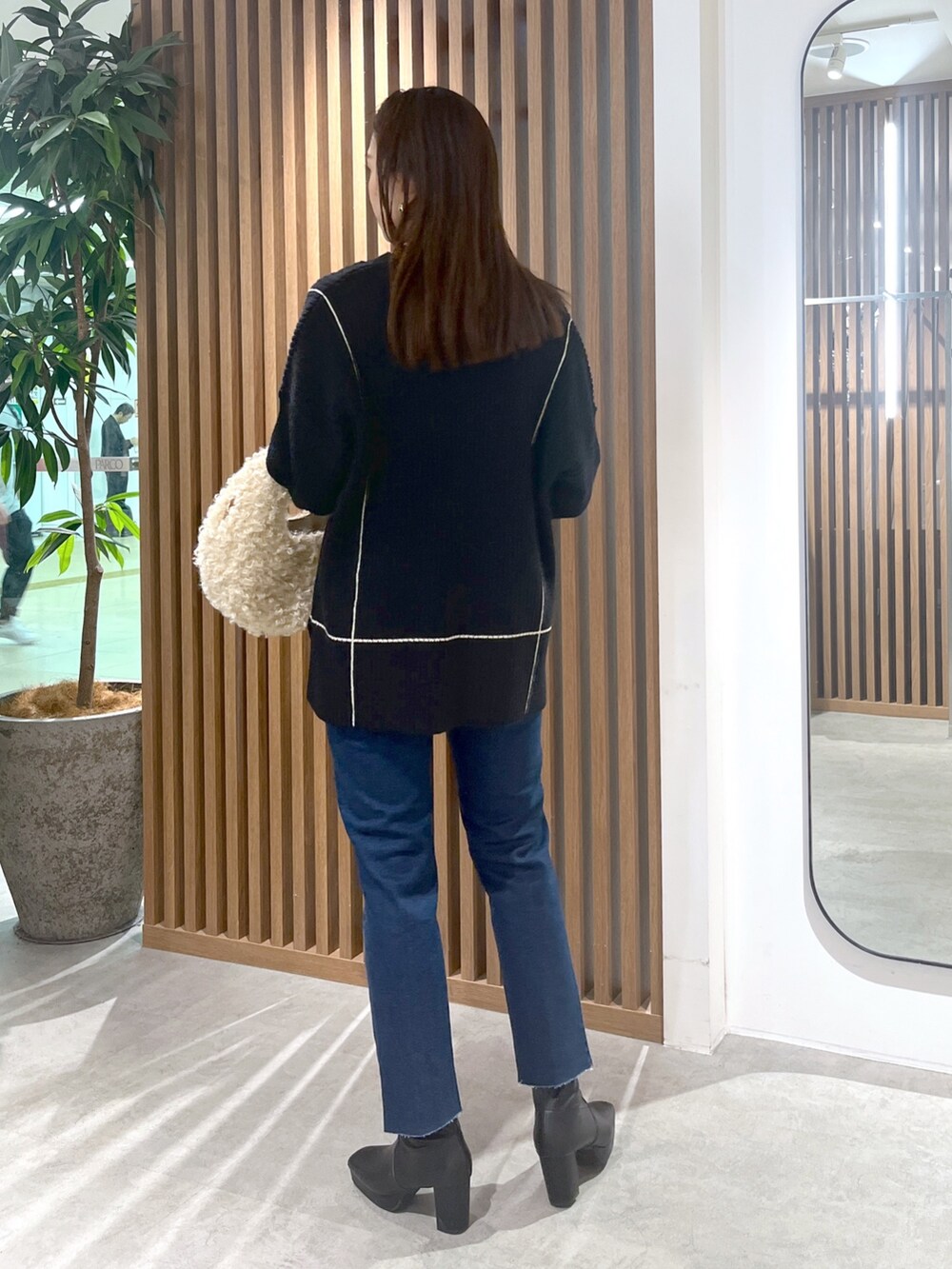 ブラック系のニット/セーター、ベージュ系のショルダーバッグ、ブルー系のデニムパンツを着用したレディースの秋コーディネートの5枚目の写真