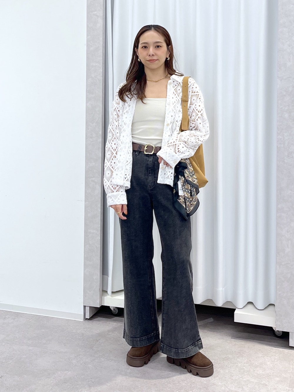 ホワイト系のブルゾン、ブラウン系のショルダーバッグ、ブラック系のデニムパンツを着用したレディースの春コーディネートの2枚目の写真