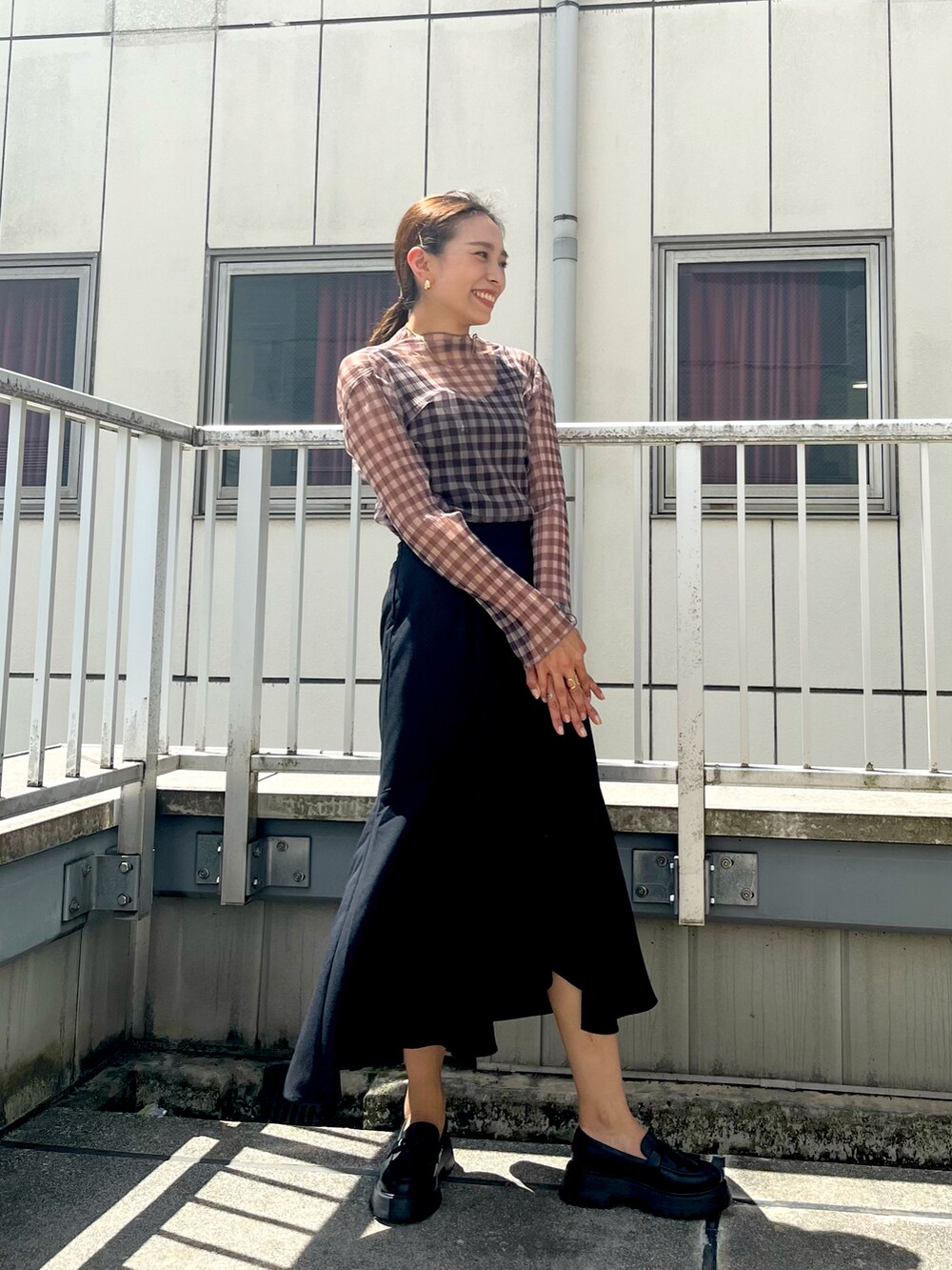 ブラウン系のTシャツ/カットソー、ブラック系のスカート、ブラック系のローファーを着用したレディースの夏コーディネートの2枚目の写真