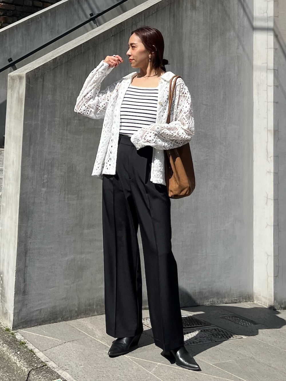 ブラック系のスラックス、ブラウン系のトートバッグ、ホワイト系のブルゾンを着用したレディースの春コーディネートの6枚目の写真