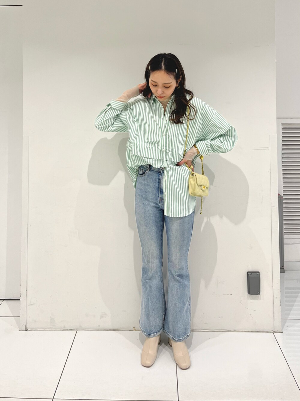 ブルー系のデニムパンツ、グリーン系のシャツ/ブラウス、イエロー系のショルダーバッグを着用したレディースの冬コーディネートの2枚目の写真