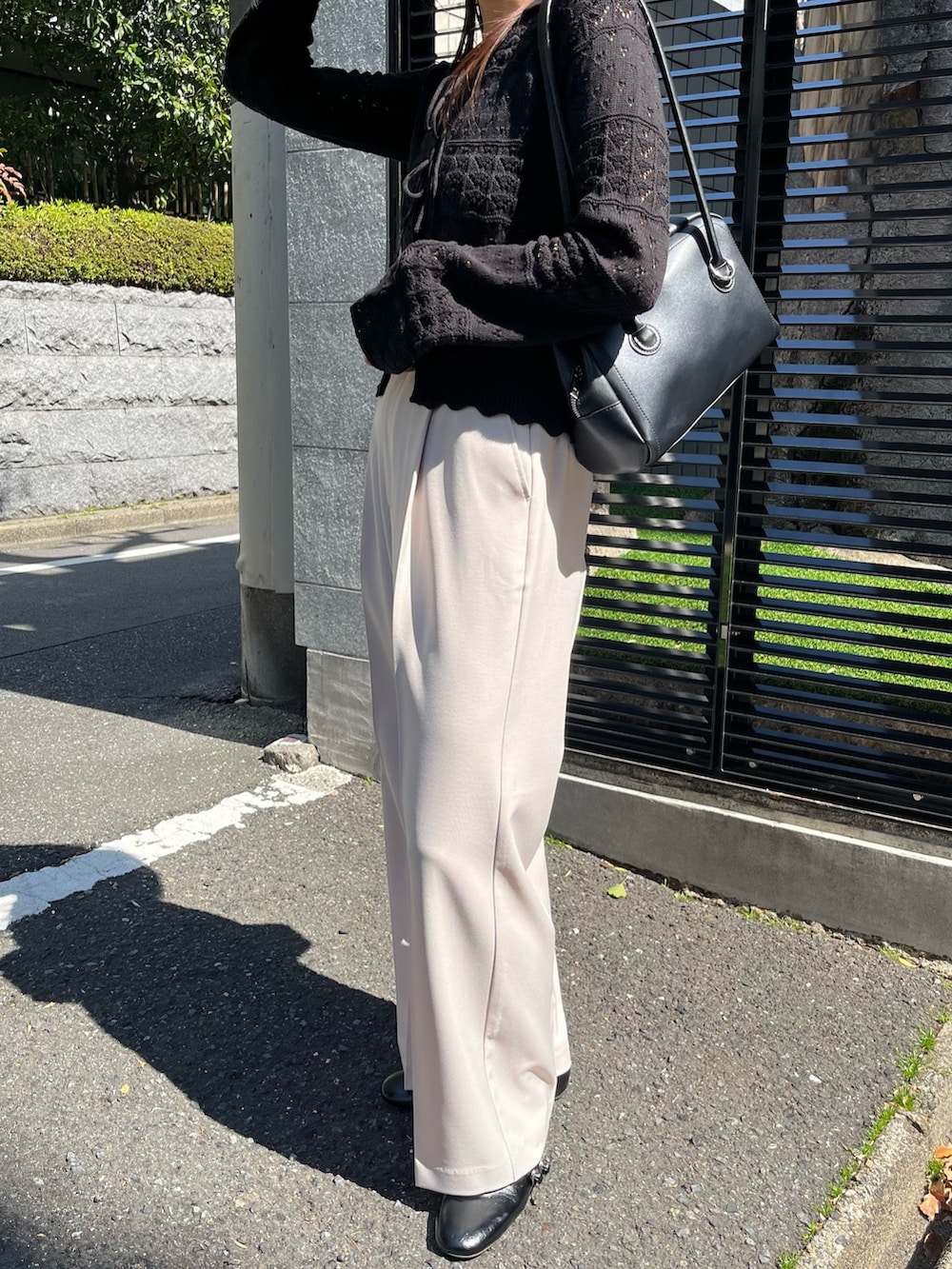 ブラック系のニット/セーター、ベージュ系のスラックス、ブラック系のパンプスを着用したレディースの春コーディネートの8枚目の写真