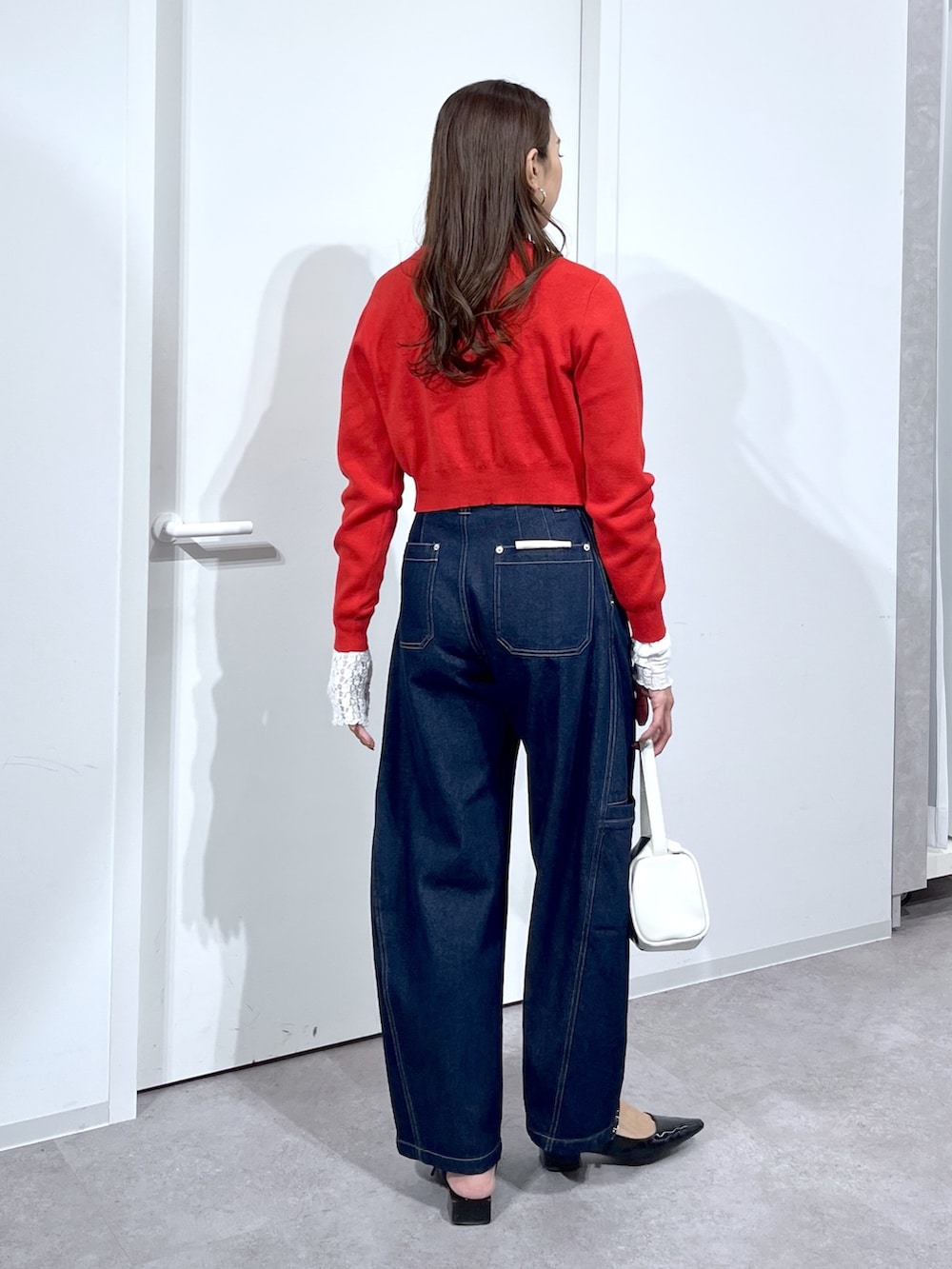 ホワイト系のTシャツ/カットソー、レッド系のニット/セーター、ブルー系のデニムパンツを着用したレディースの春コーディネートの5枚目の写真