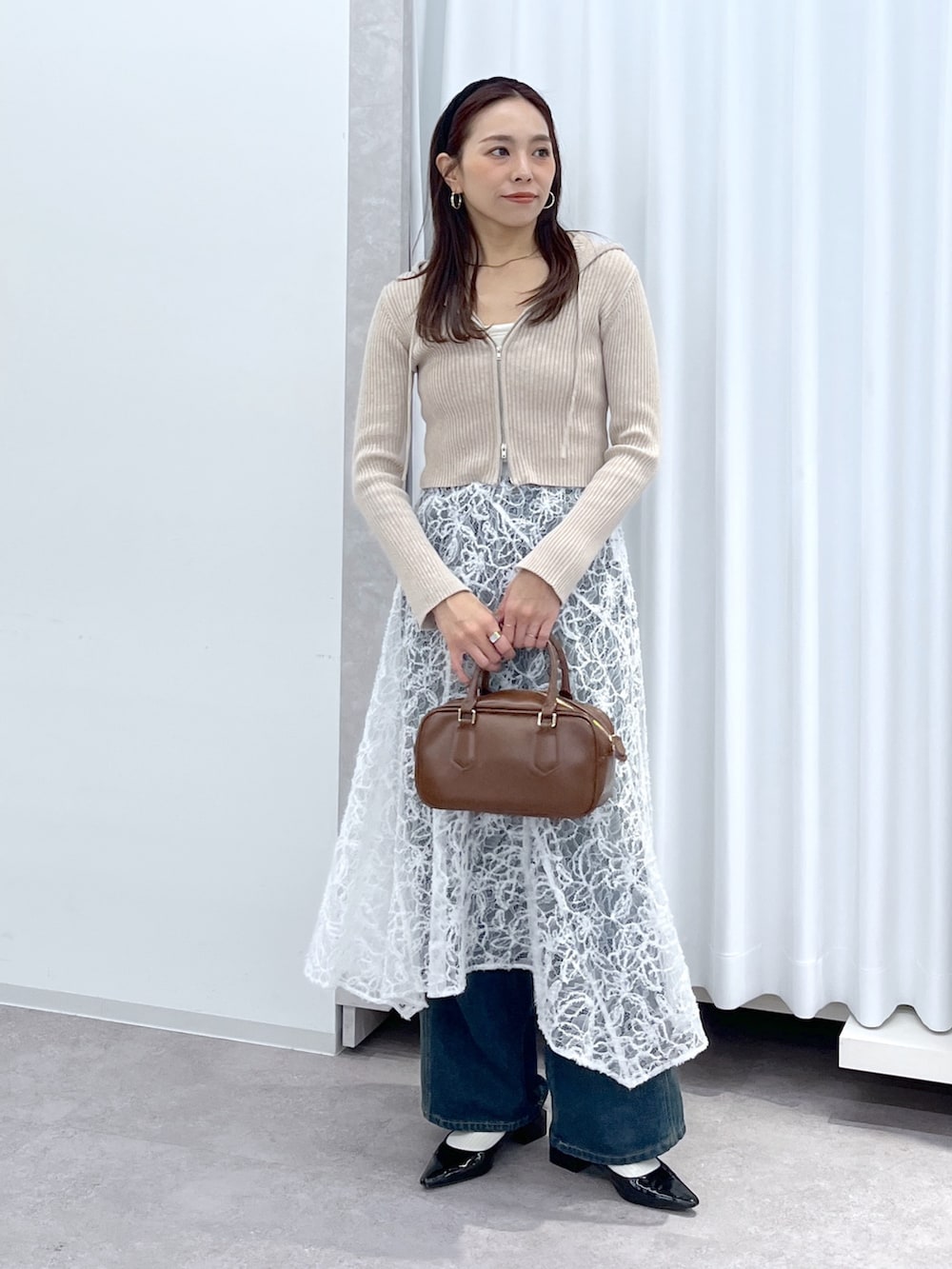 ベージュ系のニット/セーター、ブラウン系のハンドバッグ、ブルー系のデニムパンツを着用したレディースの冬コーディネートの3枚目の写真