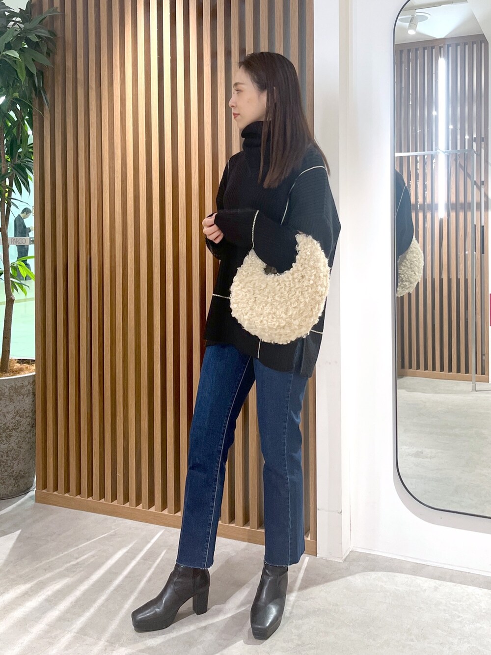 ブラック系のニット/セーター、ベージュ系のショルダーバッグ、ブルー系のデニムパンツを着用したレディースの秋コーディネートの4枚目の写真