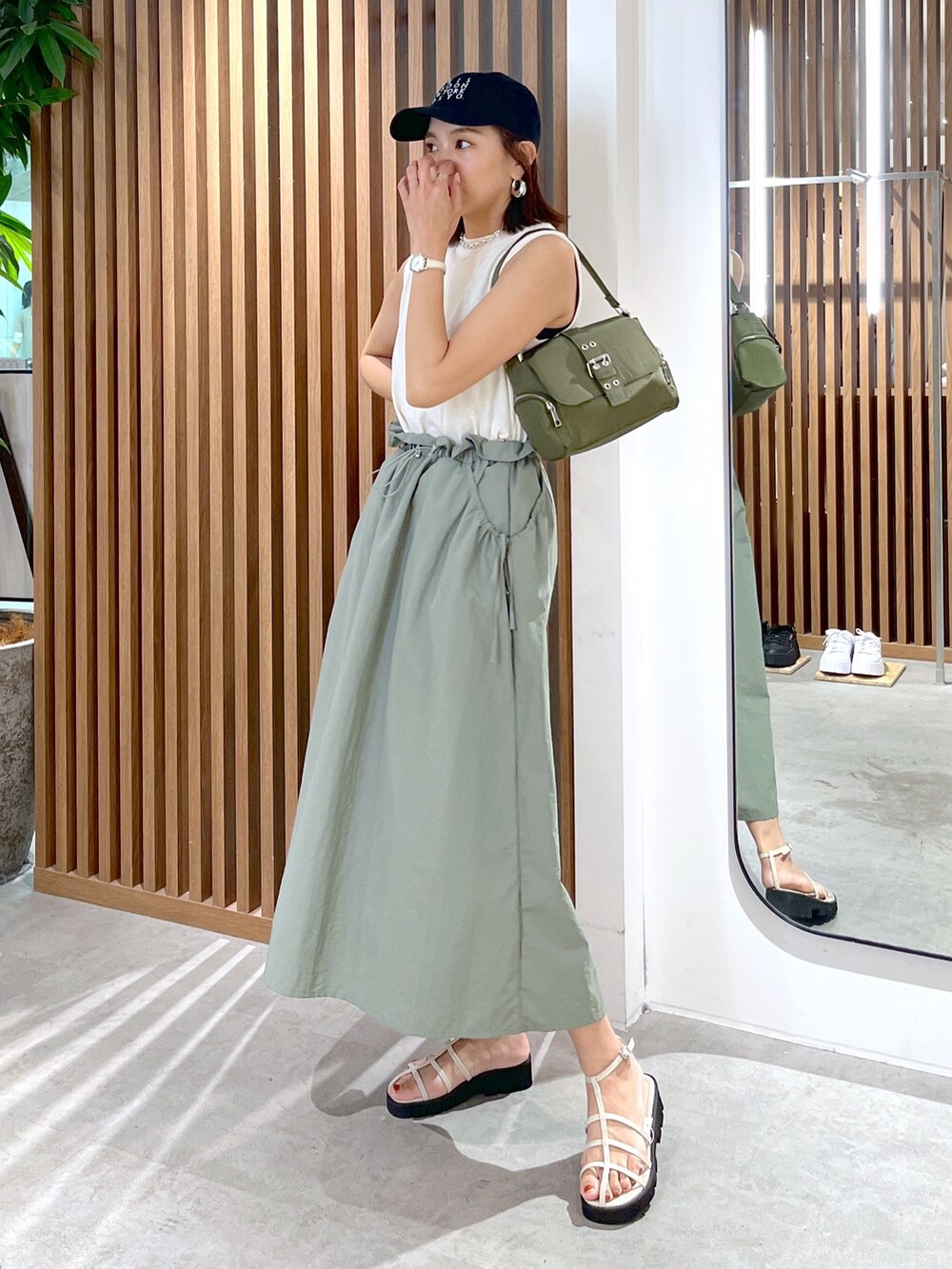 グリーン系のショルダーバッグ、グリーン系のワンピース、ホワイト系のサンダルを着用したレディースの夏コーディネートの2枚目の写真