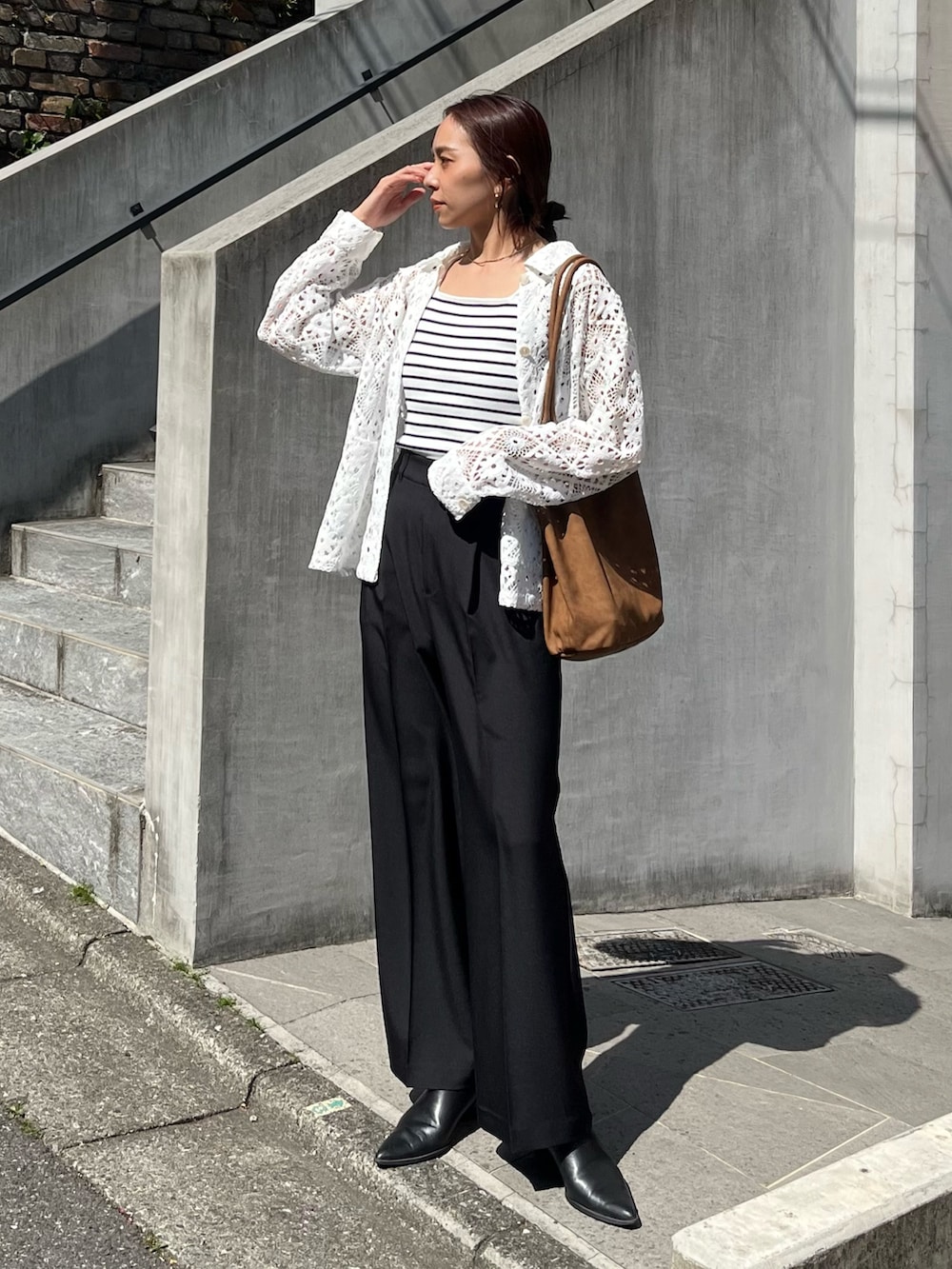 ブラック系のスラックス、ブラウン系のトートバッグ、ホワイト系のブルゾンを着用したレディースの春コーディネートの4枚目の写真