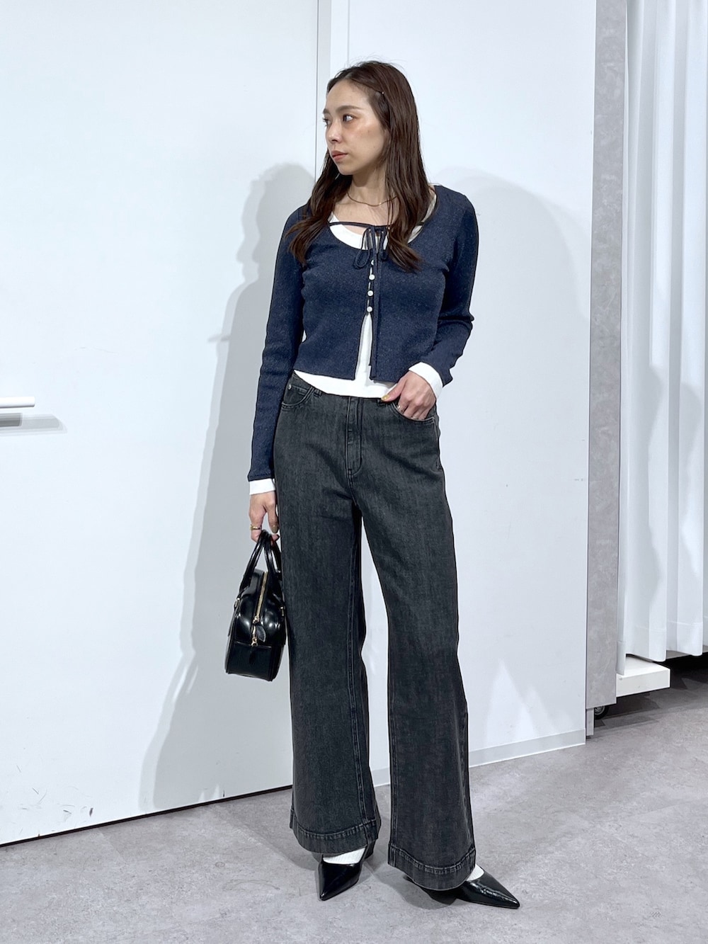 ブラック系のハンドバッグ、ブラック系のパンプス、ブラック系のデニムパンツを着用したレディースの春コーディネートの4枚目の写真