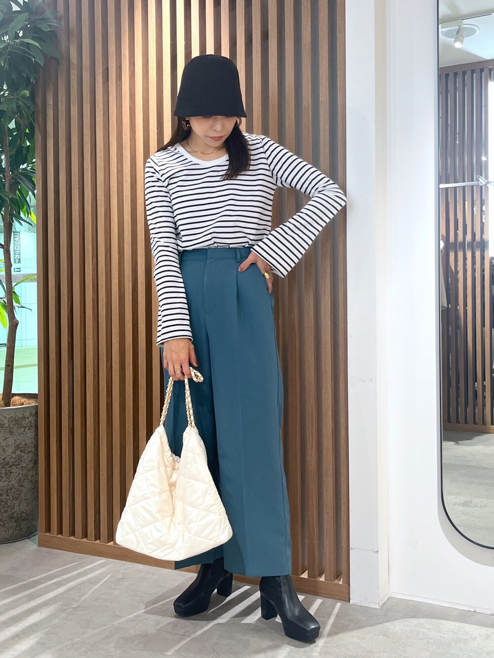 グリーン系のスラックス、ブラック系のTシャツ/カットソー、ホワイト系のトートバッグを着用したレディースの秋コーディネートの2枚目の写真