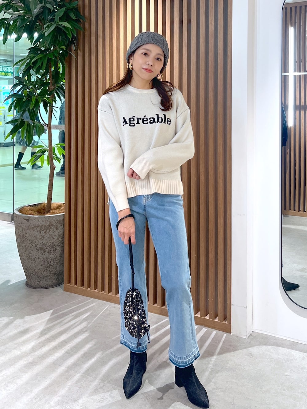 ホワイト系のニット/セーター、ブルー系のデニムパンツ、ブラック系のブーツを着用したレディースの秋コーディネートの2枚目の写真