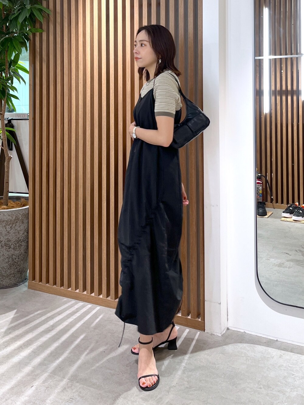 グリーン系のTシャツ/カットソー、ブラック系のショルダーバッグ、ブラック系のサンダルを着用したレディースの春コーディネートの6枚目の写真