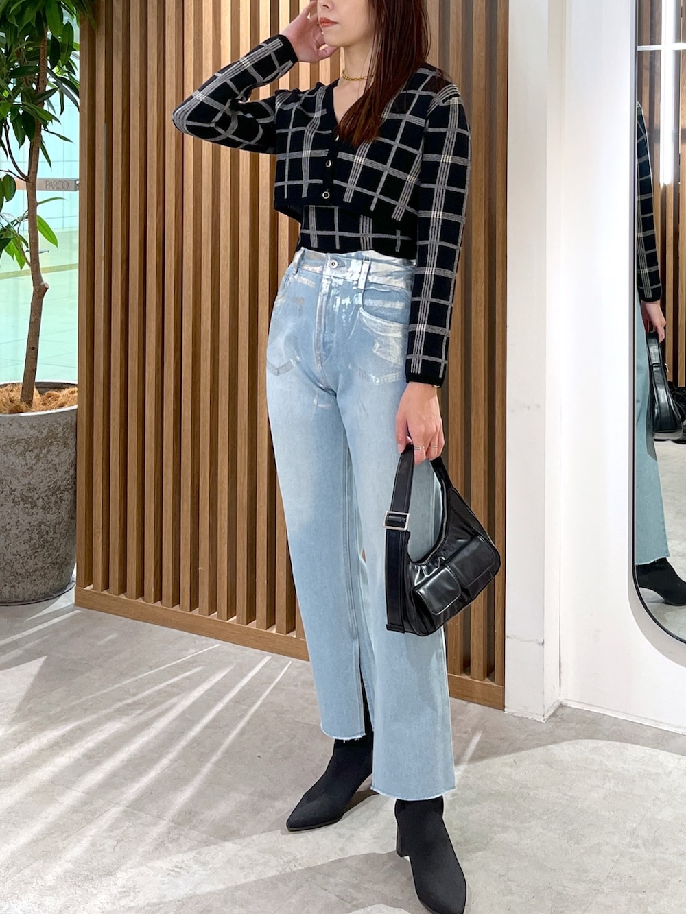 ブルー系のデニムパンツ、ブラック系のニット/セーター、ブラック系のショルダーバッグを着用したレディースの冬コーディネートの6枚目の写真